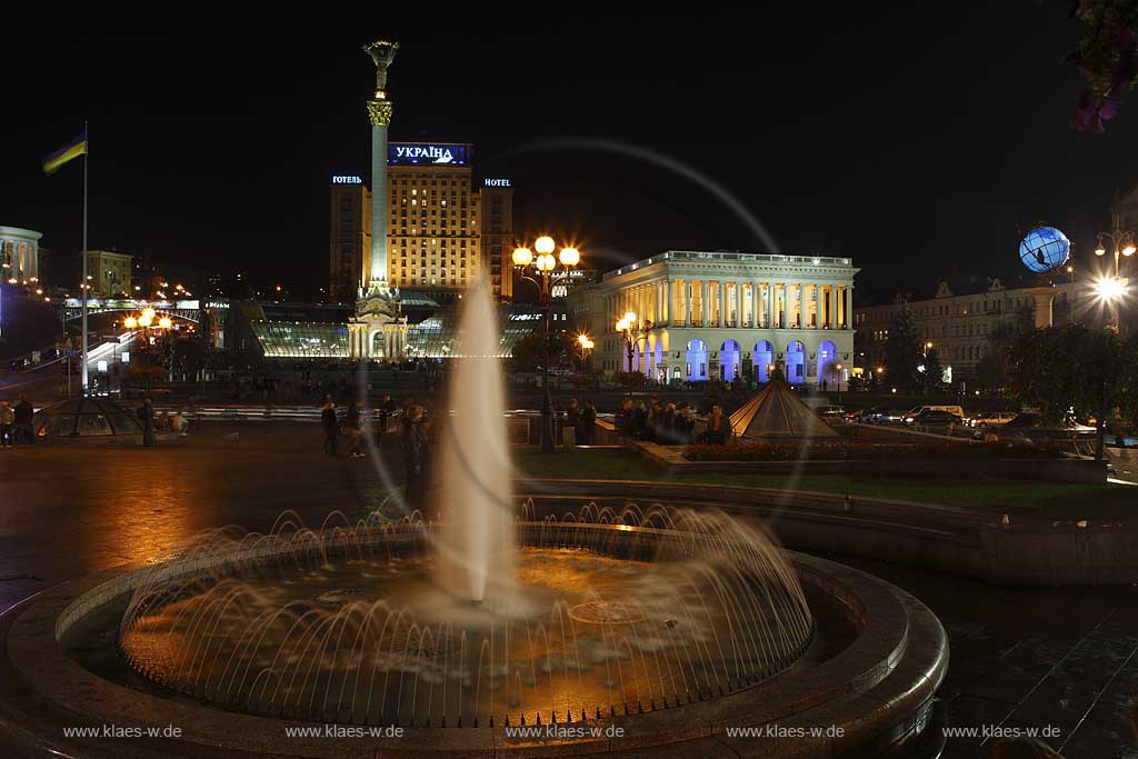 Kiew Springbrunnen vor der Saeule Sule des barocken 62 m hohen Monumentes der Unabhngigkeit mit goldenem Kapitell einer strengen Maedchenfigur Maid mit goldenem Zweig des Schneeballstrauches dahinter Hotel Ukraine Ukrajina rechts daneben das Opernstudio der Nationalen Musikakademie der Ukraine am Unabhaengigkeitsplatz Unabhngigkeitsplatz Majdan Nesaleshnosti  Majdan Nezaleznosti am Chrestschatyk Chrescatyk bei Nacht mit dem beleuchteten Globus mit dem in der Ukraine Entfernungen gemessen werden, Illumination, Wasserspielen und Menschen  . Maidan Nesaleshnosti - Independence Square at night The Khreschatyk rd. crosses Independece Square. This is Kiev's most expensive boulevard, where banks, office buildings, boutiques and chic restaurants line up.