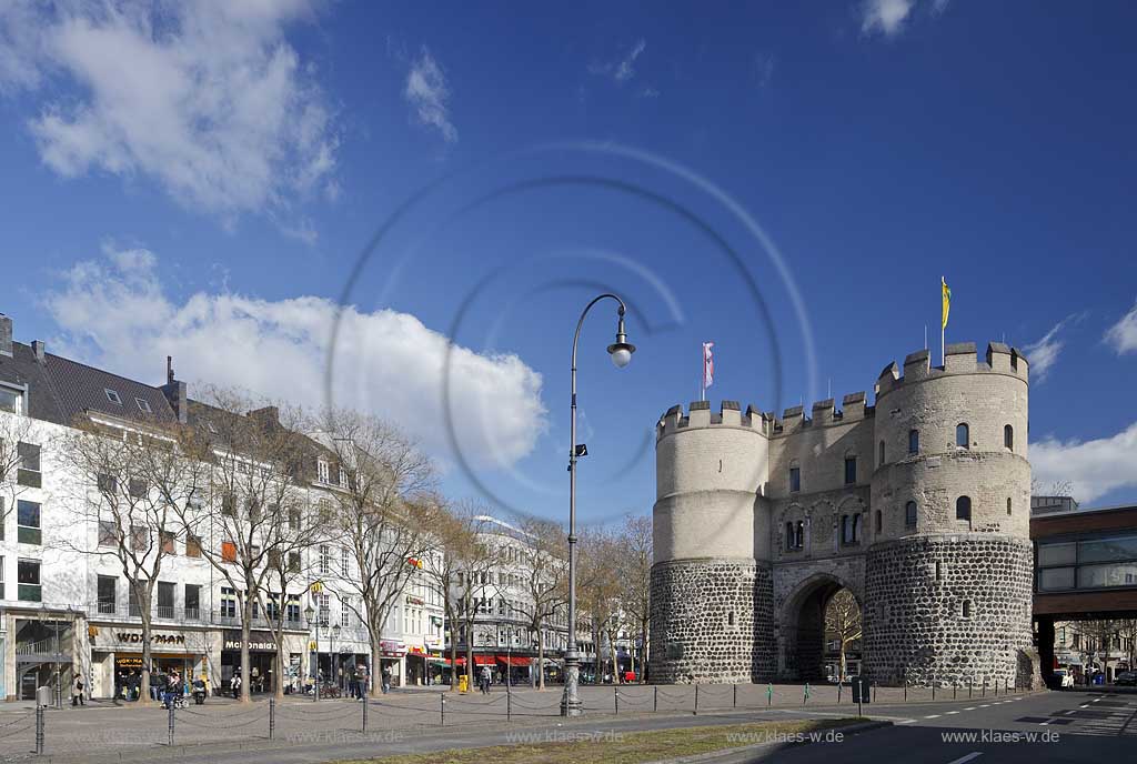 Koeln Altstadt Rudolfplatz mit Hahnentorburg Feldseite im Vorfruehling mit kahlen Baeumen, Kumuluswoilken und blauem Himmel, Cologne historical city gate in the old towm early spring time bare-brandched trees