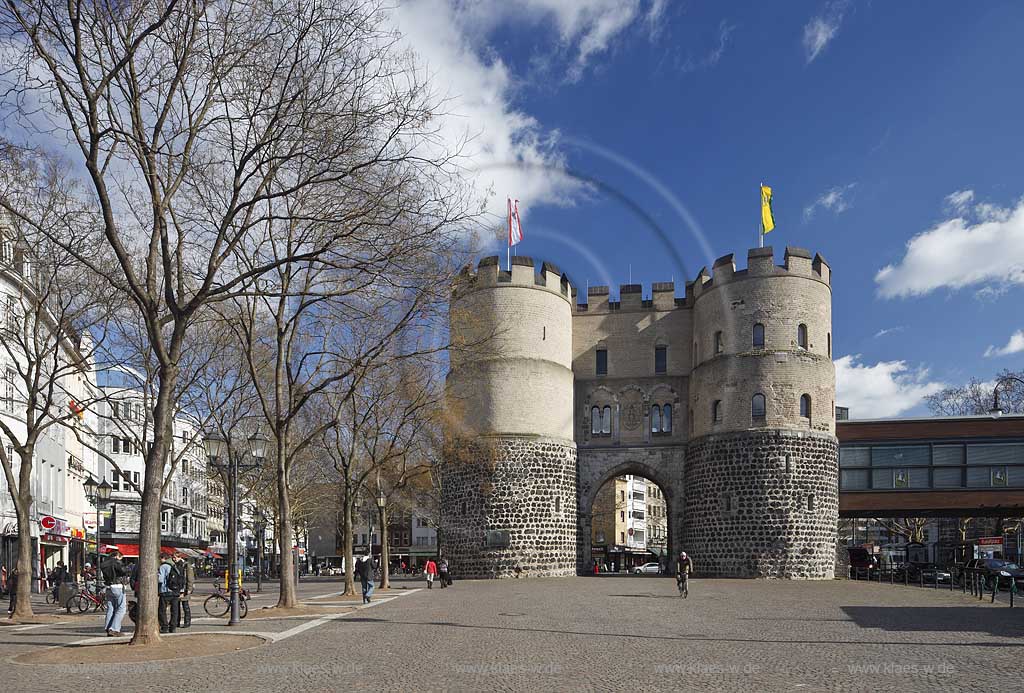 Koeln Altstadt Rudolfplatz mit Hahnentorburg Feldseite im Vorfruehling mit kahlen Baeumen, Kumuluswoilken und blauem Himmel, Cologne historical city gate in the old towm early spring time bare-brandched trees