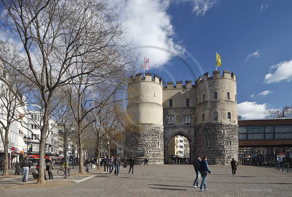 Koeln Altstadt Rudolfplatz mit Hahnentorburg Feldseite im Vorfruehling mit kahlen Baeumen, Kumuluswoilken und blauem Himmel, Cologne historical city gate in the old towm early spring time bare-brandched trees