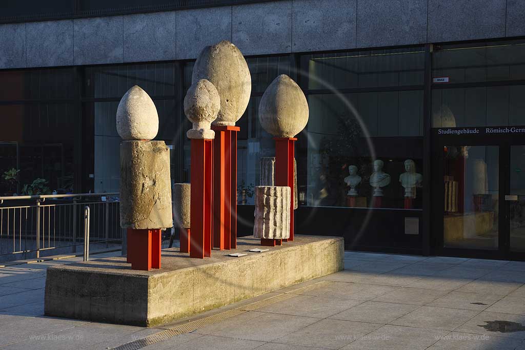 Kln, Skulptur Fuenf Saulentrommen und steinerne Pinienzapfen aus Granit bzw. Kalkstein auf einer Sockelinsel neben dem Roemisch Germanischen Museeum, Sculptures from limestone and granite in Old Town of Cologne beside the Roman Germanic Museeum of Cologne