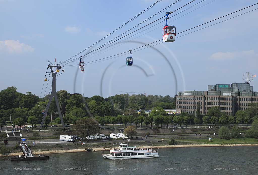 Koeln, Blick mit Rhein Seilbahn, der ersten Seilschwebebahn ueber einen Fluss, dem DEVK Versicherung Verwaltungsgebaeude mit der Koelner Kugel, ein Kunstwerk von H.A. Schult sowie einem Schiff der Weissen Flotte  Colonia 5 mit Passagieren, Anlagestelle Zoo / Flora Seilbahn; Cologne view with aereal passanger line, cableway, Rhine River, excursion boat, passangers, building with artwork of H.A. Schult: Cologne ball or Cologne globe