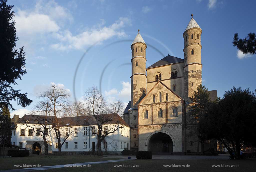 Koeln Altstadt, romanische Kirche Sankt Pantaleon Aussenansicht im Fruehling mit kahlen Baeumen im waremn Licht der Abendsonne; Cologne old town romanesque church St. Pantaleon