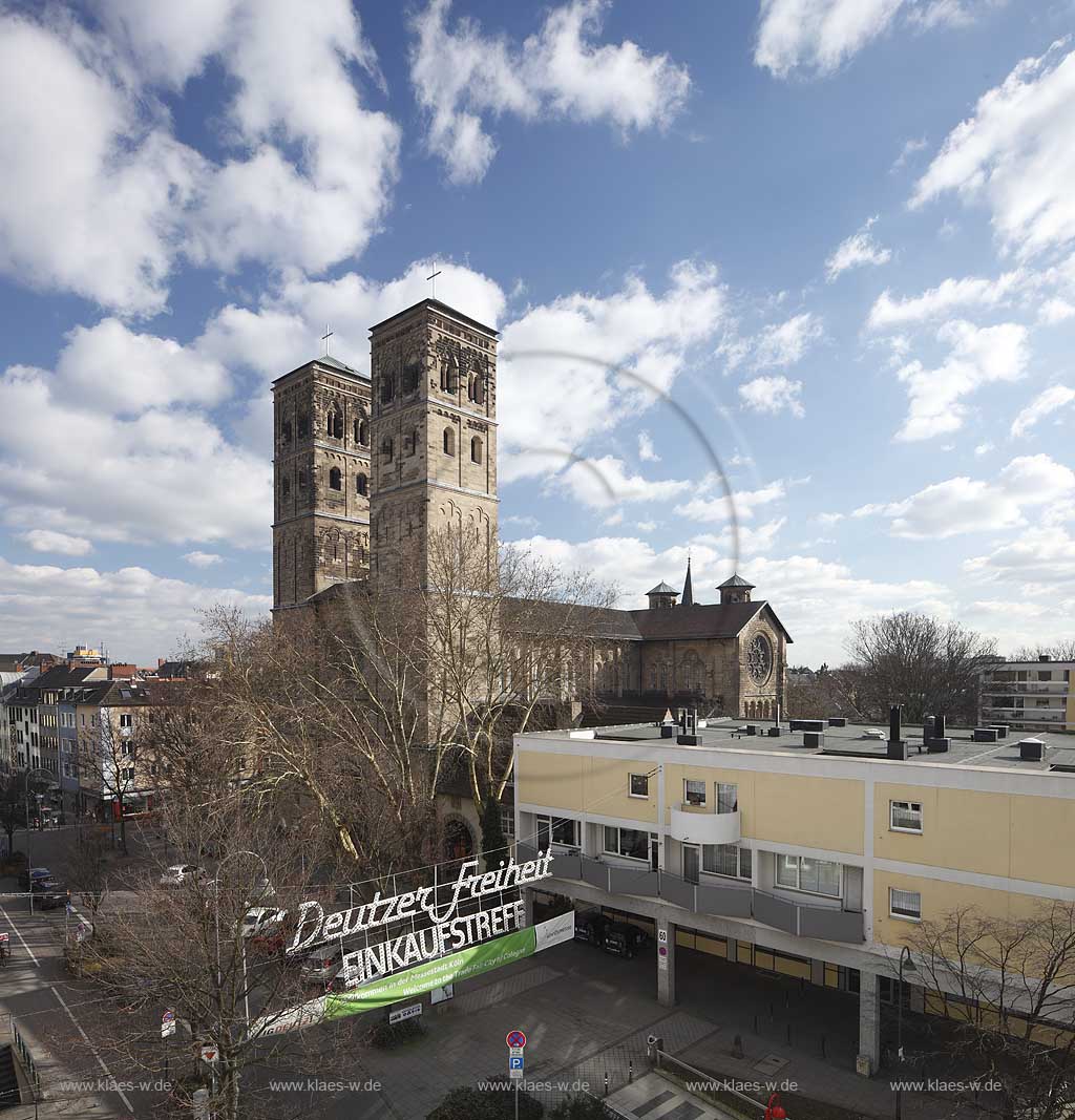 Koeln Deutz, Aussenansicht von Nordwesten zu den beiden Kirchtuermen der Pfeilerbasilika St. Heribert im Fruehling mit kahlen Baeumen und Kumuluswolken, Deutzer Freiheit; Cologne Deutz northwest side with steeples of basilica St. Heribert