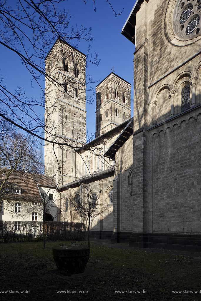 Koeln Deutz, Aussenansicht Hofseite von Suedwesten zu den beiden Kirchtuermen der Pfeilerbasilika St. Heribert im Fruehling mit kahlen Baeumen; Cologne Deutz southwest side with steeples of basilica St. Heribert