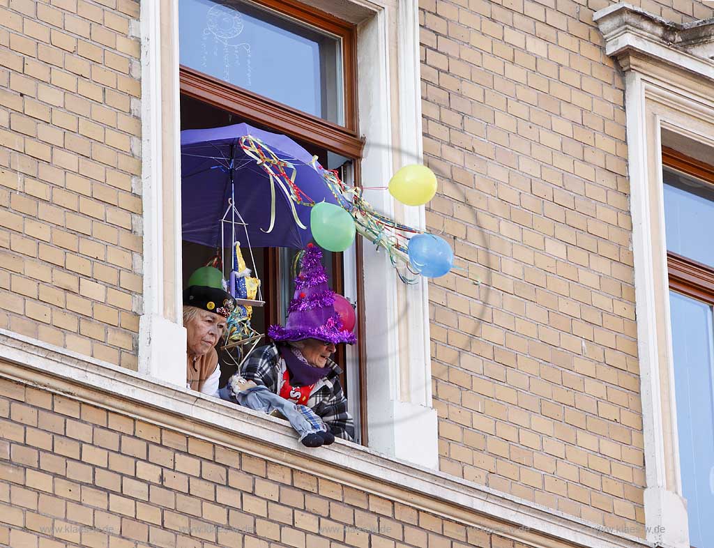 Koeln Ehrenfeld, Karneval, zwei verkleidete Frauen schauen aus euinem Fenster auf den Veedelszug am Veilchendienstag; Cologne carnival, masked women looking out of a window