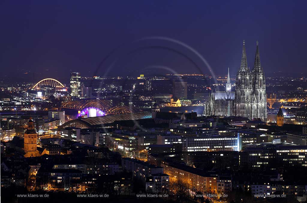 Koeln Blick zur spaeten blauen Stunde mit beleuchteten Kirchtuermen von links nach rechts Sankt Ursula, Alt Sankt Heribert, Dom, Gross Sankt Martin, dem Rathausturm und den Bruecken Hohenzollernbruecke mit Musical Dome und Severinsbruecke, weiter hinten im Stadtteil Deutz sichtbar das beleuchtete Hochhaus Koelntriangel und die Lanxess Arena, Cologne extreme panoramic view with dome and several well known buildings and churches an bridges during late blue hour in illumination