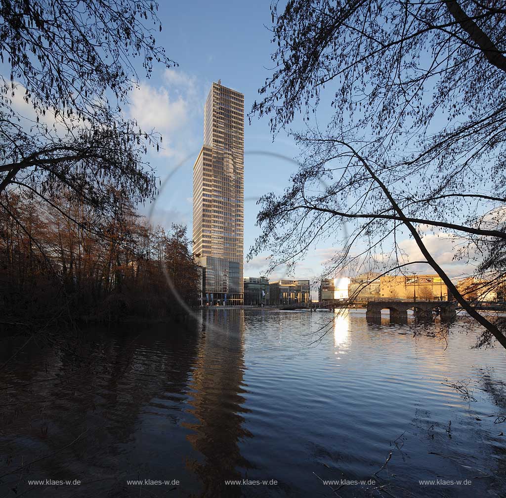  Koeln. Neustadt Nord Medianpark, Gebaeudeensemplex mit Koelnturm, dem mit 148,5 Metern ohne und 165,48 Metern mit Antenne hoechsten Koelner Buerohaus inm Licht der untergehenden Sonne, Abendstimmung mit Spiegelbild im Fruehling mit kahlen Baeumen; Cologne Media Park with the largest office building in Cologne, the Koelnturm Colognetower in evening sunset Light with  mirror image