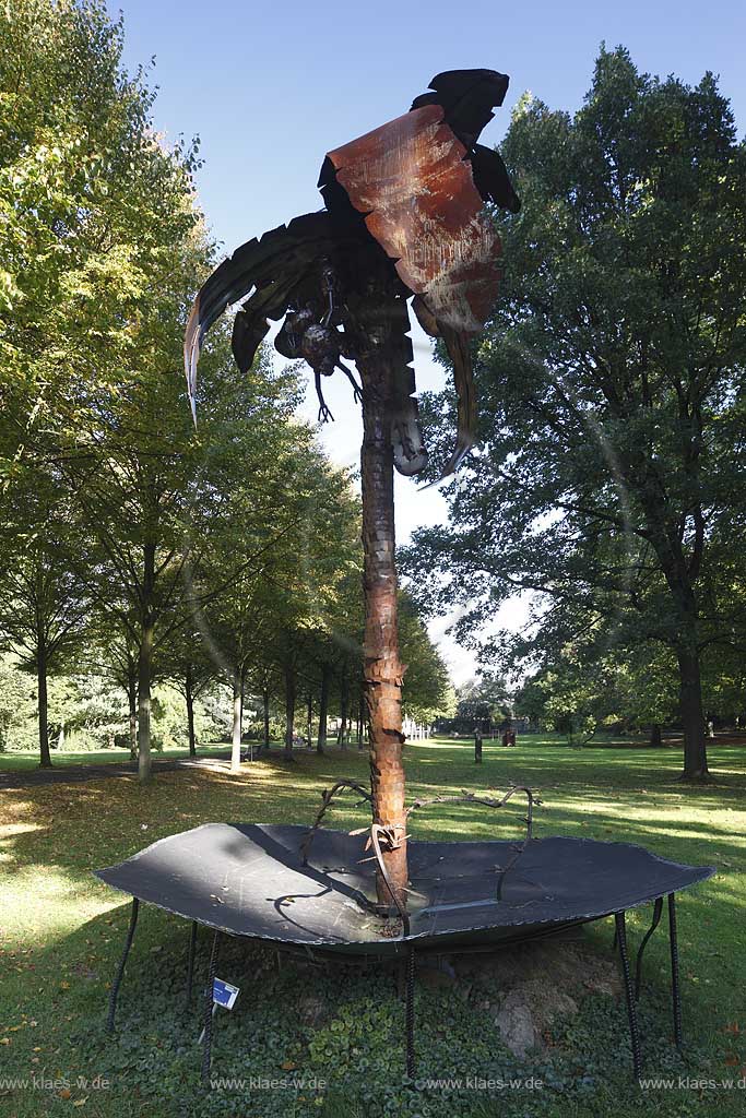 Koeln-Stammheim Schlosspark Skulpturenpark, Tobi Moehring zeigt in seiner Arbeit, der Metallskulptur Affenklima, 2007 wie nah die Phantasie hier schon an der Wirklichkeit ist. Im 2006/2007 so extrem warmen Winter stellte sich der aus Stammheim stammende Kuenstler eine naheliegende Frage: Wie lange dauert es noch, bis in Deutschland die Affen unter den Baeumen turnen ? Seine Antwort zeigt eine Palme deren Kokosnsse leuchten und unter der kleine Affen turnen; Cologne-Stammheim park of castle with sculpture from Tobi Moehring 