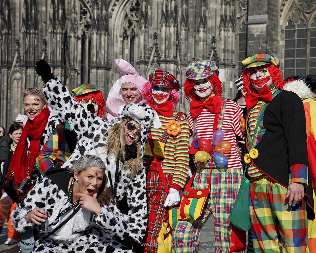 Koeln Domplatte waehrend Altweiberfasnacht, Altweiberfasching, Altweiber feiernde Moehnen und jJecke, verkleidet, Clowns in bunten Kostuemen im Karneval vor dem Dom