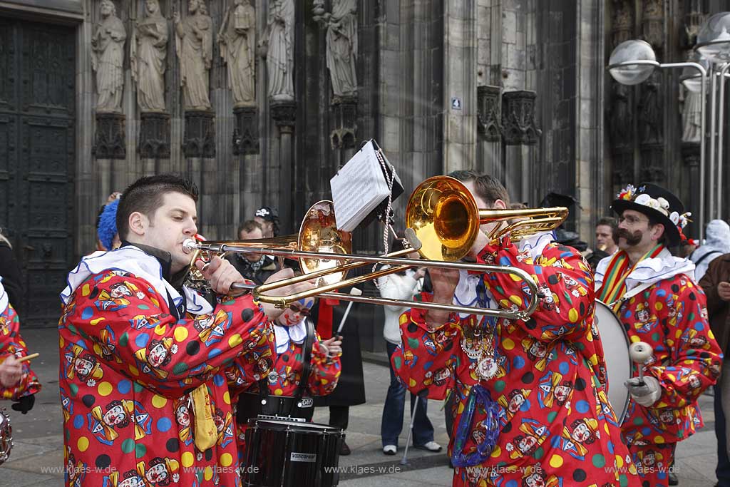 Koeln Domplatte waehrend Altweiberfasnacht, Altweiberfasching, Altweiber spielende Kapelle Musikgruppe in bunten Kostuemen vor dem Dom