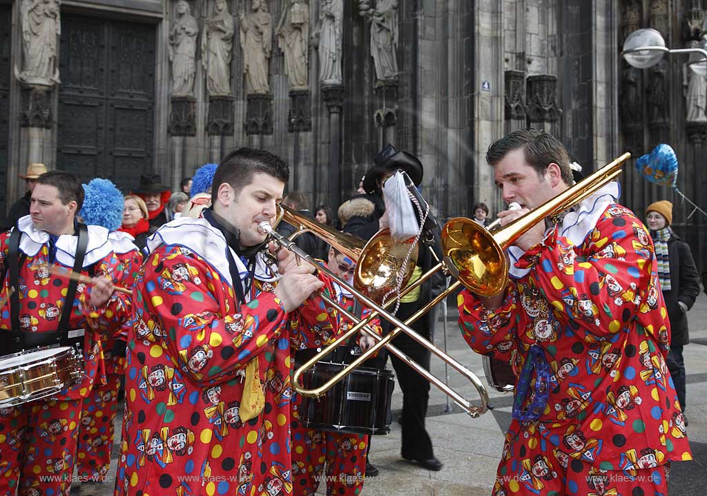 Koeln Domplatte waehrend Altweiberfasnacht, Altweiberfasching, Altweiber spielende Kapelle Musikgruppe in bunten Kostuemen vor dem Dom