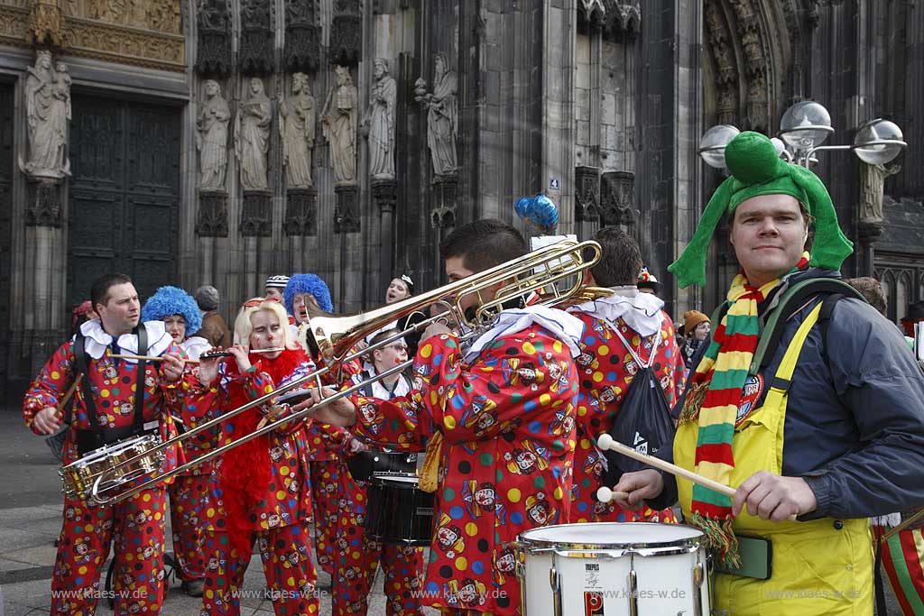 Koeln Domplatte waehrend Altweiberfasnacht, Altweiberfasching, Altweiber spielende Kapelle Musikgruppe in bunten Kostuemen vor dem Dom