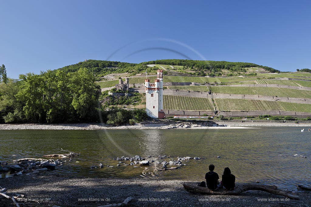 Bingen, Mauseturm im Rhein bei Niedrigwasser mit Spiegelbild, im Hintergrund Ruine Ehrenfels, Ruedesheim, verliebtes Paar, Siluette, sitzt im Vordergund im Bild und schaut auf des Panorama; Bingen, Maeuseturm in Rhine at low water with reflection, in background ruin Ehrenfels, Ruedesheim, pair in love in the foregraound.