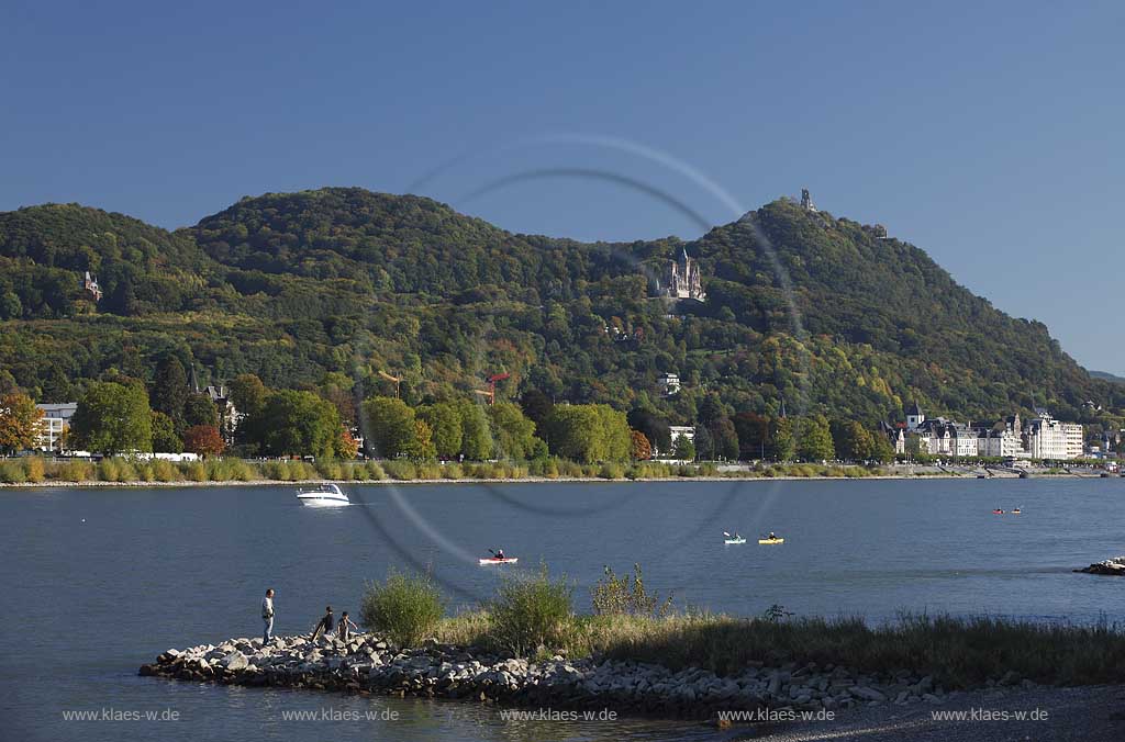 Bonn Rheinufer bei Oberkassel mit Blick ueber den Rhein zum Siebengebirge mit Drachenfels und Drachenburg, Rhein mit Motorboot und Kanus mit Personen auf Buhne aus Stein in Herbststimmung; Bonn Rhine coast at Oberkassel with view over the Rhine to the Siebengebirge with Dragoncliff and Dragoncastle, Rhine with motorboat and canoes with people at spur dyke in autumn atmopshere