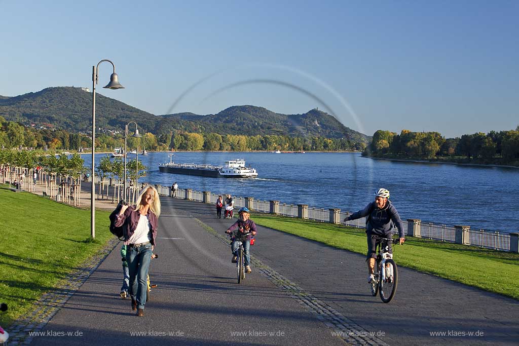 Bonn Rheinpromenade mit Blick ueber den Rhein zum Petersberg mit Drachenfels und Drachenburg, Rheinpromenade mit Wanderern und Radfahrern, Bonn Rhine promenade with view over the Rhine to the Petersberg with Dragoncliff and Dragoncastle, promenade with hiker and bicyclists