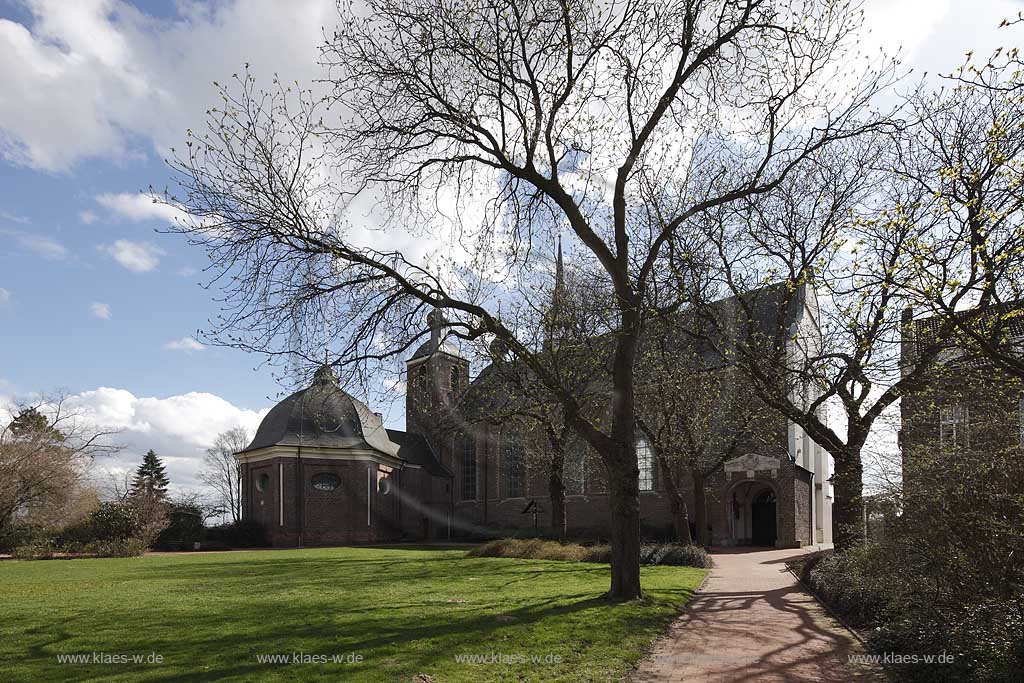 Kamp-Lintfort Abteiplatz mit Kloster Kamp im Fruehling mit kahlen Baeumen, Cumuluswolken, blauem Himmel im Fruehling, Gegenlicht, Kloster Kamp ist ein Kloster auf dem Gebiet der Stadt Kamp-Lintfort, deren Name sich vom Kloster herleitet. Es wurde 1123 gegruendet und war das erste Zisterzienserkloster im damaligen deutschsprachigen Raum. Die Klosteranlage liegt auf einem Huegel (Kamper Berg); Kamp-Lintfort abbey Kamp in spring with cumulus clouds and blue sky