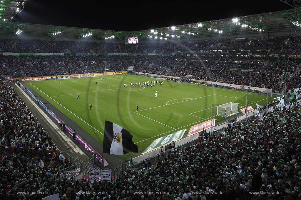 Moenchengladbach Borussiapark Stadion Innennansicht waehrend eines Fussballspiels Borussia Monchengladbach gegen FC Schalke 4 mit Flutlicht ausverkauft mit voll besetzten Raengen vor Spielbeginn; Mannschaften auf dem Spielfeld wehende Fahnren Fussballfans Zuschauer Tribuenen; Moenchengladbach Stadium internal picture during Football game Borussia Moenchengladbach vs. FC Schalke 04 with fans and flags