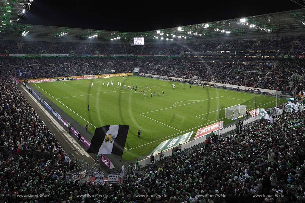 Moenchengladbach Borussiapark Stadion Innennansicht waehrend eines Fussballspiels Borussia Monchengladbach gegen FC Schalke 4 mit Flutlicht ausverkauft mit voll besetzten Raengen vor Spielbeginn; Mannschaften auf dem Spielfeld wehende Fahnren Fussballfans Zuschauer Tribuenen; Moenchengladbach Stadium internal picture during Football game Borussia Moenchengladbach vs. FC Schalke 04 with fans and flags