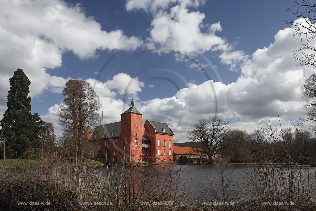 Neukirchen-Vlyn Schloss Bloemersheim, Wasserschloss aus dem Spaetmittelalter, Blick zur rueckwaertigen Seite ueber den Schlossweiher im Fruehling mit kahlen Bauemen,Wolkenstimmung windig bis stuermisch; Kamp-Lintfort water moated castle Bloemersheim in springtime  impression with clouds