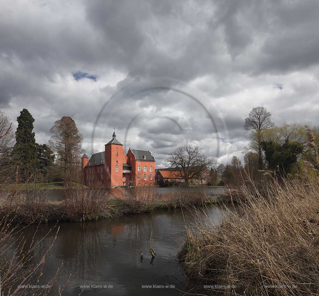 Neukirchen-Vlyn Schloss Bloemersheim, Wasserschloss aus dem Spaetmittelalter, Blick zur rueckwaertigen Seite ueber den Schlossweiher im Fruehling mit kahlen Bauemen,Wolkenstimmung windig bis stuermisch; Kamp-Lintfort water moated castle Bloemersheim in springtime  impression with clouds