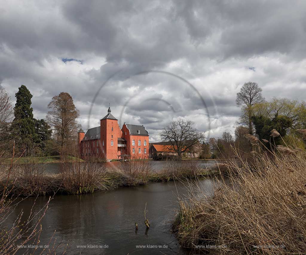 Neukirchen-Vlyn Schloss Bloemersheim, Wasserschloss aus dem Spaetmittelalter, Blick zur rueckwaertigen Seite ueber den Schlossweiher im Fruehling mit kahlen Bauemen,Wolkenstimmung windig bis stuermisch; Kamp-Lintfort water moated castle Bloemersheim in springtime  impression with clouds