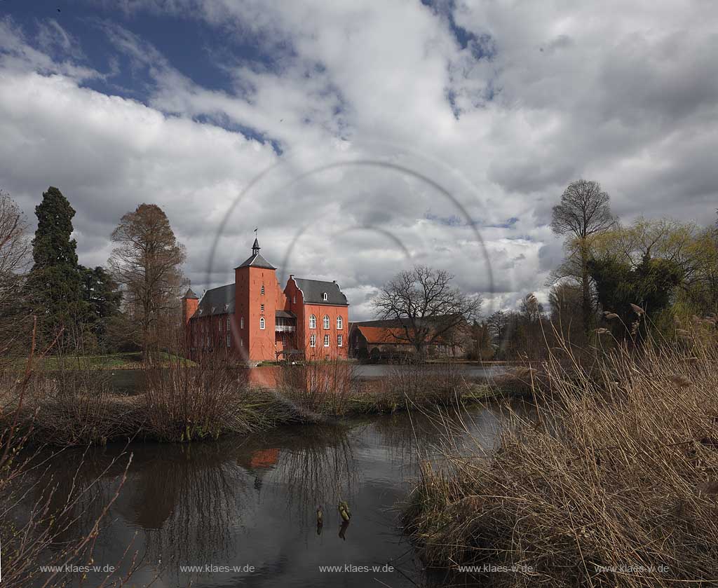 Neukirchen-Vlyn Schloss Bloemersheim, Wasserschloss aus dem Spaetmittelalter, Blick zur rueckwaertigen Seite ueber den Schlossweiher im Fruehling mit kahlen Bauemen,Wolkenstimmung windig bis stuermisch; Kamp-Lintfort water moated castle Bloemersheim in springtime  impression with clouds