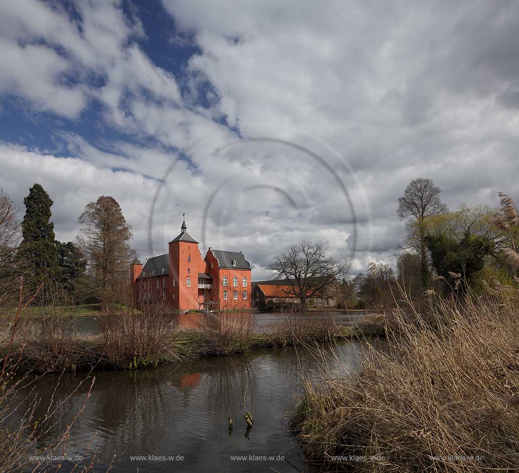 Neukirchen-Vlyn Schloss Bloemersheim, Wasserschloss aus dem Spaetmittelalter, Blick zur rueckwaertigen Seite ueber den Schlossweiher im Fruehling mit kahlen Bauemen,Wolkenstimmung windig bis stuermisch; Kamp-Lintfort water moated castle Bloemersheim in springtime  impression with clouds