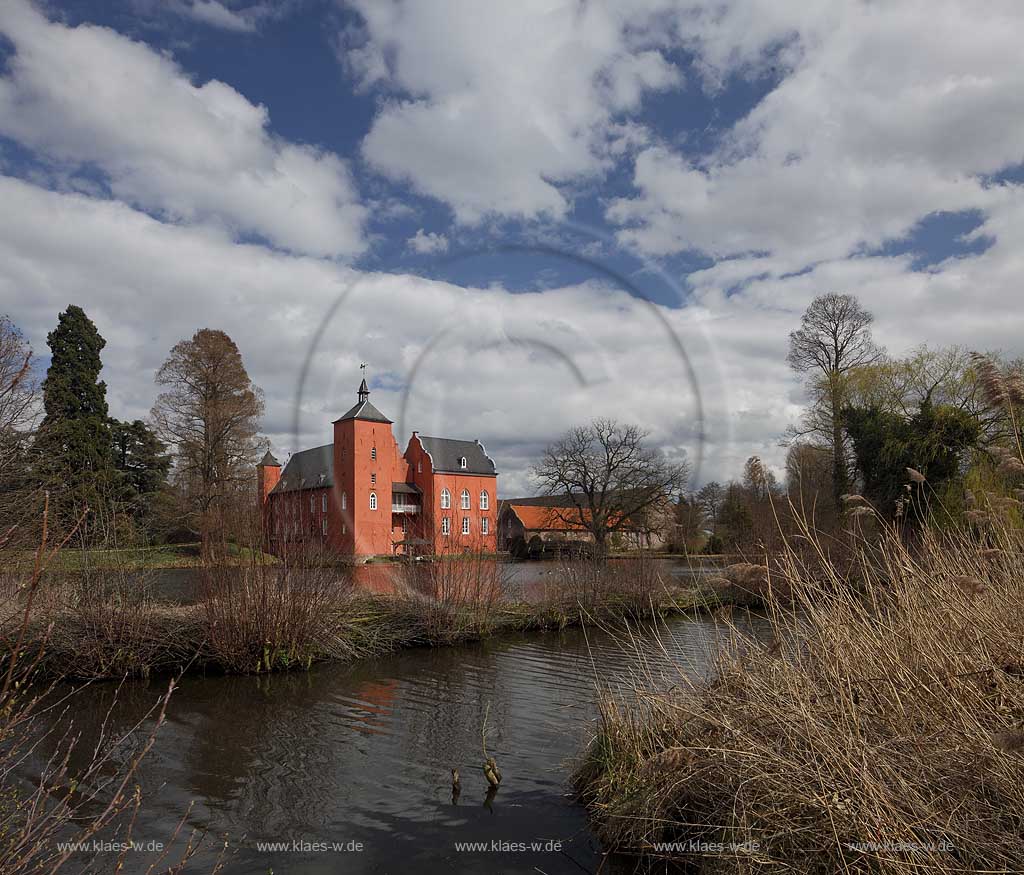 Neukirchen-Vlyn Schloss Bloemersheim, Wasserschloss aus dem Spaetmittelalter, Blick zur rueckwaertigen Seite ueber den Schlossweiher im Fruehling mit kahlen Bauemen,Wolkenstimmung windig bis stuermisch; Kamp-Lintfort water moated castle Bloemersheim in springtime  impression with clouds