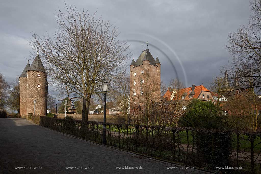 Xanten, Stimmung mit dunklen Wolken,sonnig, Blick zum Klever Tor mit Kriemhildmuehle im Hintergrund und Kirchturmspitzen des Doms rechts am Bildrand, Fruehling mit kahlen Baeumen; Kleve impression with town gate Klever Tor in springtime with dark clouds