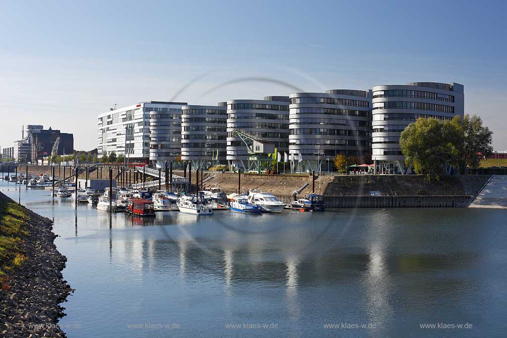 Duisburg Innenhafen der nach den Plaenen des britischen Star-Architekten Nicholas Grimshaw unter dem Namen "Five Boats" entstendene  Buerokomplex, der gepraegt ist von fuenf sechsgeschossigen Baukoerpern in Schiffsform, die auf einem fr Einzelhandel und Gastronomie genutzten Erdgeschoss mit ihrem jeweiligen Bug in Richtung Wasser weisen 