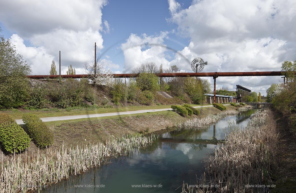 Duisburg Meiderich. Emscherpromenade mit Klarwasserkanal, Hochgasleitung, Windenergieturm, Wolkenstimmung. Der Landschaftspark Duisburg-Nord, auch kurz LaPaDu ist ein etwa 200 Hektar groer Landschaftspark rund um ein stillgelegtes Huettenwerk in Duisburg-Meiderich, das im Rahmen der IBA (Internationale Bauausstellung Emscher Park) entstand. Der Landschaftspark ist einer der Ankerpunkte der Europaeischen Route der Industriekultur sowie der Route der Industriekultur im Ruhrgebiet;  Duisburg-Meiderich, the Meiderich ironworks are the main feature in the North Duisburg Landscape Park, clear water canal, wind turbine tower