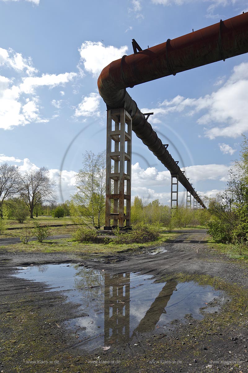 Duisburg Meiderich. Nacktflaeche auf dem Zechengelaende mit Hochgasleitung und Spiegelbild in Wasserlache auf Schlackegrund. Der Landschaftspark Duisburg-Nord, auch kurz LaPaDu ist ein etwa 200 Hektar groer Landschaftspark rund um ein stillgelegtes Huettenwerk in Duisburg-Meiderich, das im Rahmen der IBA (Internationale Bauausstellung Emscher Park) entstand. Der Landschaftspark ist einer der Ankerpunkte der Europaeischen Route der Industriekultur sowie der Route der Industriekultur im Ruhrgebiet;  Duisburg-Meiderich, the Meiderich ironworks are the main feature in the North Duisburg Landscape Park, naked aere at cole mine aera with hight gas line.