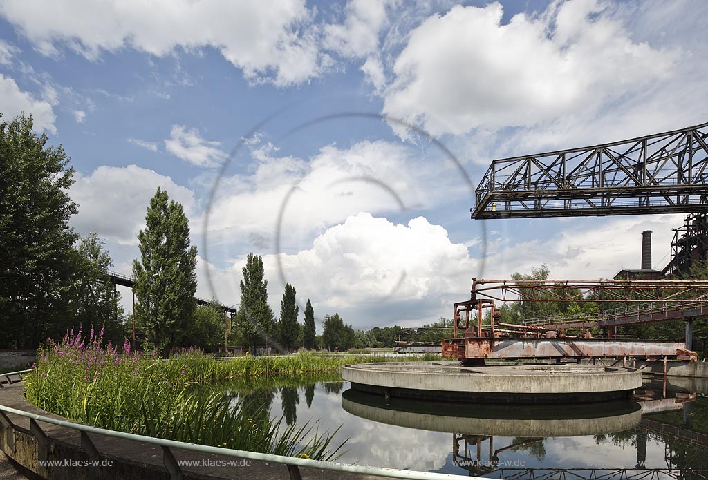 Duisburg Meiderich. Rundklaerbecken mit Blut-Weiderich, Bock-Kran, Wolkenstimmung. Der Landschaftspark Duisburg-Nord, auch kurz LaPaDu ist ein etwa 200 Hektar grosser Landschaftspark rund um ein stillgelegtes Huettenwerk in Duisburg-Meiderich, das im Rahmen der IBA (Internationale Bauausstellung Emscher Park) entstand. Der Landschaftspark ist einer der Ankerpunkte der Europaeischen Route der Industriekultur sowie der Route der Industriekultur im Ruhrgebiet;  Duisburg-Meiderich, the Meiderich ironworks are the main feature in the North Duisburg Landscape Park, sedimentation tank