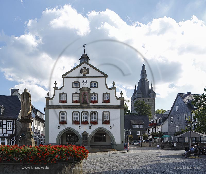 Brilon, Markt mit Petrusbrunnen und Rathaus. Das Briloner Rathaus zaehlt zu den aeltesten Rathaeusern in Deutschland. Zweigeschossig, wohl in der Mitte des 13. Jahrhunderts als Zunfthaus erbaut. Doppelarkade im Erdgeschoss mit Bildstock von 1688 am Mittelpfeiler. Doppelt geschweifte Barockgiebel nach einem Entwurf des waldeckischen Baumeisters "Johann Matthias Kitz", mittige Nische mit einer Figur des Stadtpatrons St. Petrus. Dachreiter bekroent, im Hintergrund der Turm der Probsteikirche; Brilon, fountain Petrusbrunnen and town hall.