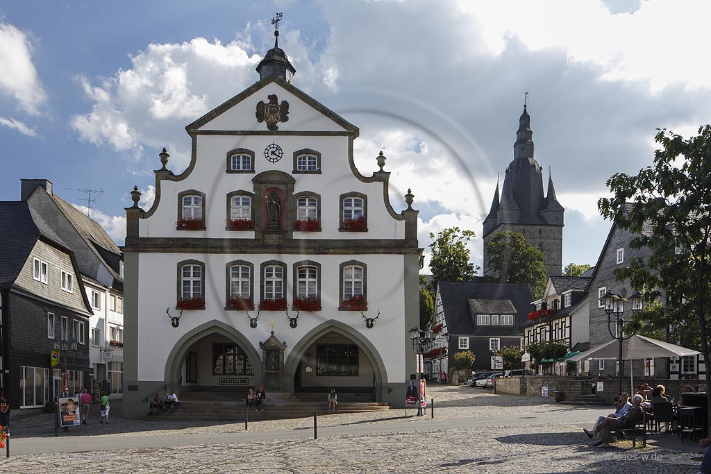 Brilon, Markt mit  Rathaus. Das Briloner Rathaus zaehlt zu den aeltesten Rathaeusern in Deutschland. Zweigeschossig, wohl in der Mitte des 13. Jahrhunderts als Zunfthaus erbaut. Doppelarkade im Erdgeschoss mit Bildstock von 1688 am Mittelpfeiler. Doppelt geschweifte Barockgiebel nach einem Entwurf des waldeckischen Baumeisters "Johann Matthias Kitz", mittige Nische mit einer Figur des Stadtpatrons St. Petrus. Dachreiter bekroent, im Hintergrund der Turm der Probsteikirche; Brilon, market square and town hall.