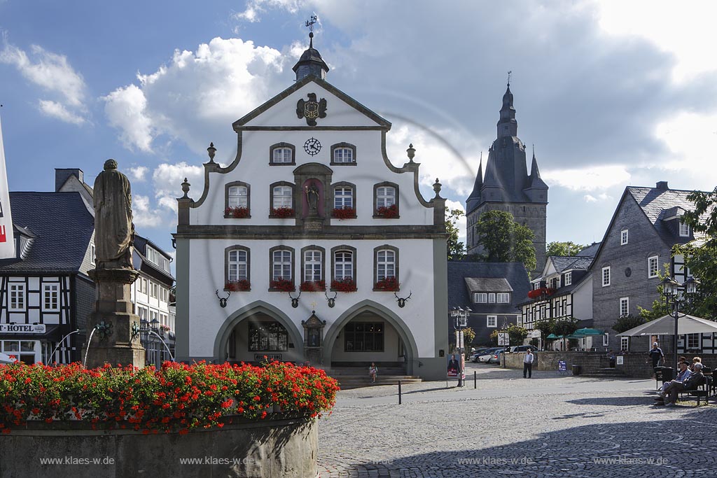 Brilon, Markt mit Petrusbrunnen und Rathaus. Das Briloner Rathaus zaehlt zu den aeltesten Rathaeusern in Deutschland. Zweigeschossig, wohl in der Mitte des 13. Jahrhunderts als Zunfthaus erbaut. Doppelarkade im Erdgeschoss mit Bildstock von 1688 am Mittelpfeiler. Doppelt geschweifte Barockgiebel nach einem Entwurf des waldeckischen Baumeisters "Johann Matthias Kitz", mittige Nische mit einer Figur des Stadtpatrons St. Petrus. Dachreiter bekroent, im Hintergrund der Turm der Probsteikirche; Brilon, fountain Petrusbrunnen and town hall.