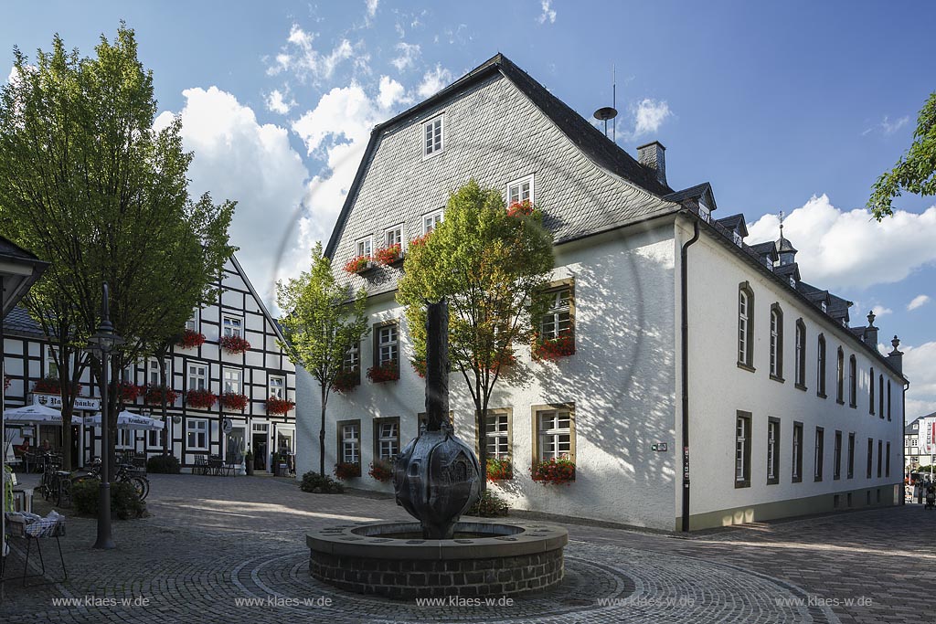 Brilon, Rathaus,  Rueck- und Seitenansicht mit dem Geschichtsbrunnen vom Madfelder Kuenstler "Theodor Sprenger" gestaltet. Der Brunnen zeigt auf einer bronzenen Stele Szenen aus den Briloner Schnadezuegen und verschiedene Motive mit Bezug zur Stadt. Auf dem Rand der Brunnenschale sind die Wappen der Briloner Ortsteile als Bronzetafeln angebracht; Brilon, townhall.