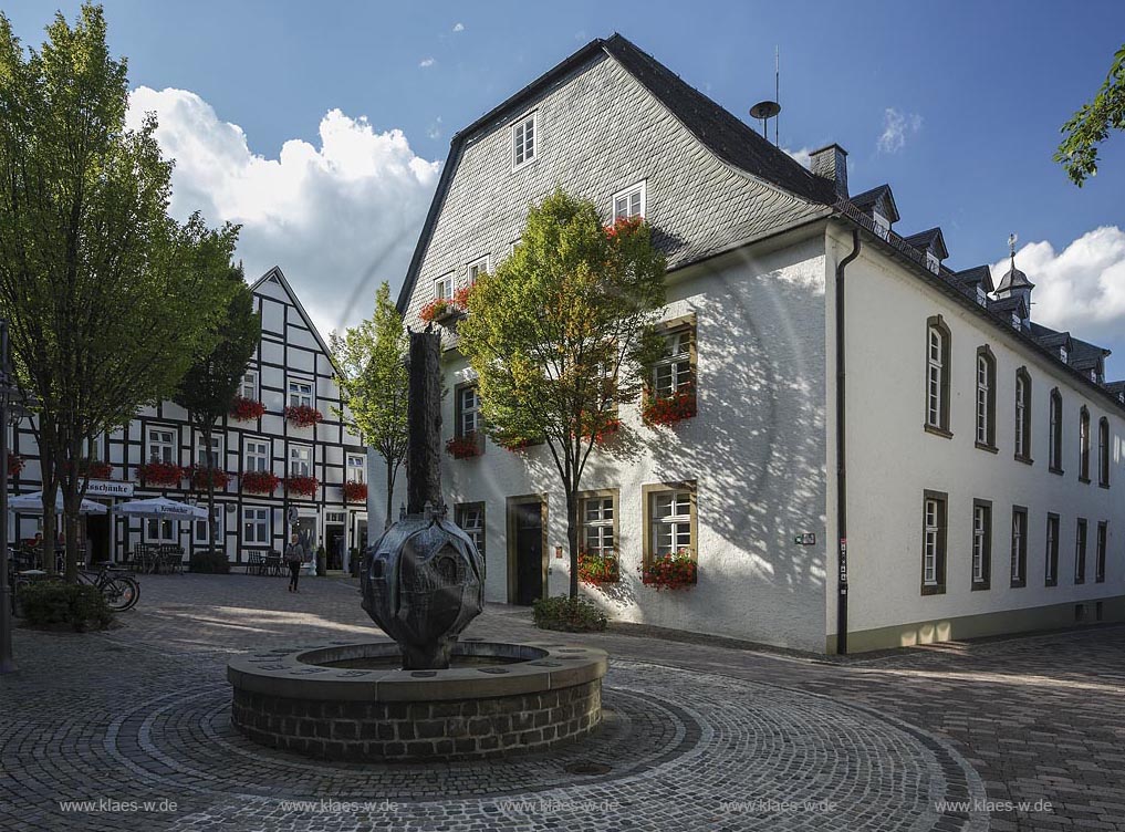 Brilon, Rathaus,  Rueck- und Seitenansicht mit dem Geschichtsbrunnen vom Madfelder Kuenstler "Theodor Sprenger" gestaltet. Der Brunnen zeigt auf einer bronzenen Stele Szenen aus den Briloner Schnadezuegen und verschiedene Motive mit Bezug zur Stadt. Auf dem Rand der Brunnenschale sind die Wappen der Briloner Ortsteile als Bronzetafeln angebracht; Brilon, townhall.