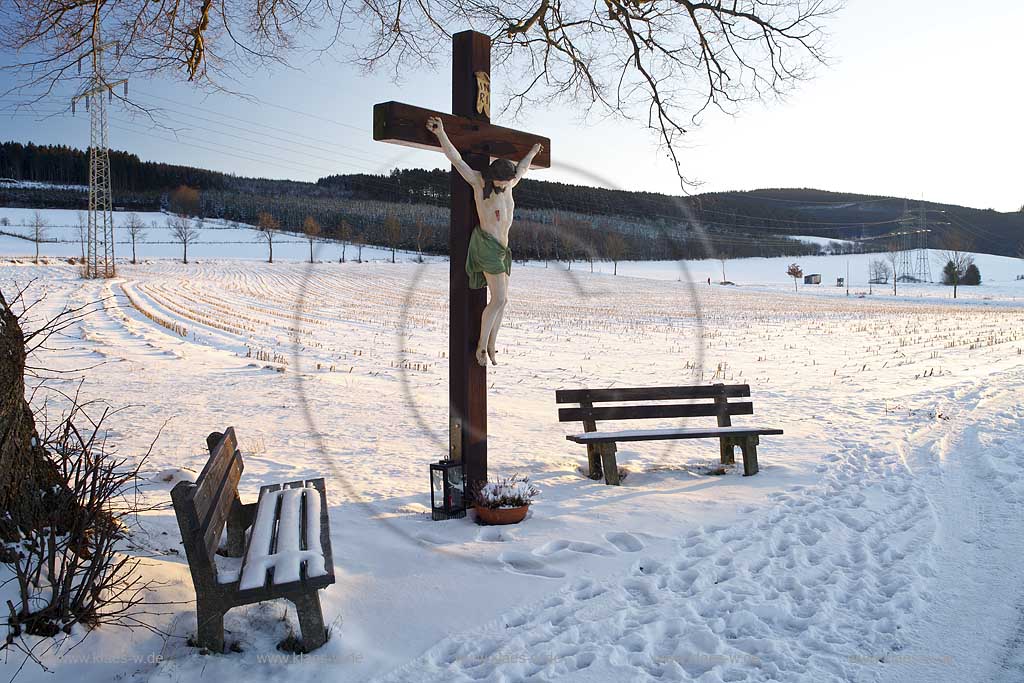 Schmallenberg Flurkreuz in verscheiter Winterlandschaft im warmen Licht der tief stehenden Abendsonne; Cruzifix in snow-covered winter landscape in warm light of evening sun.