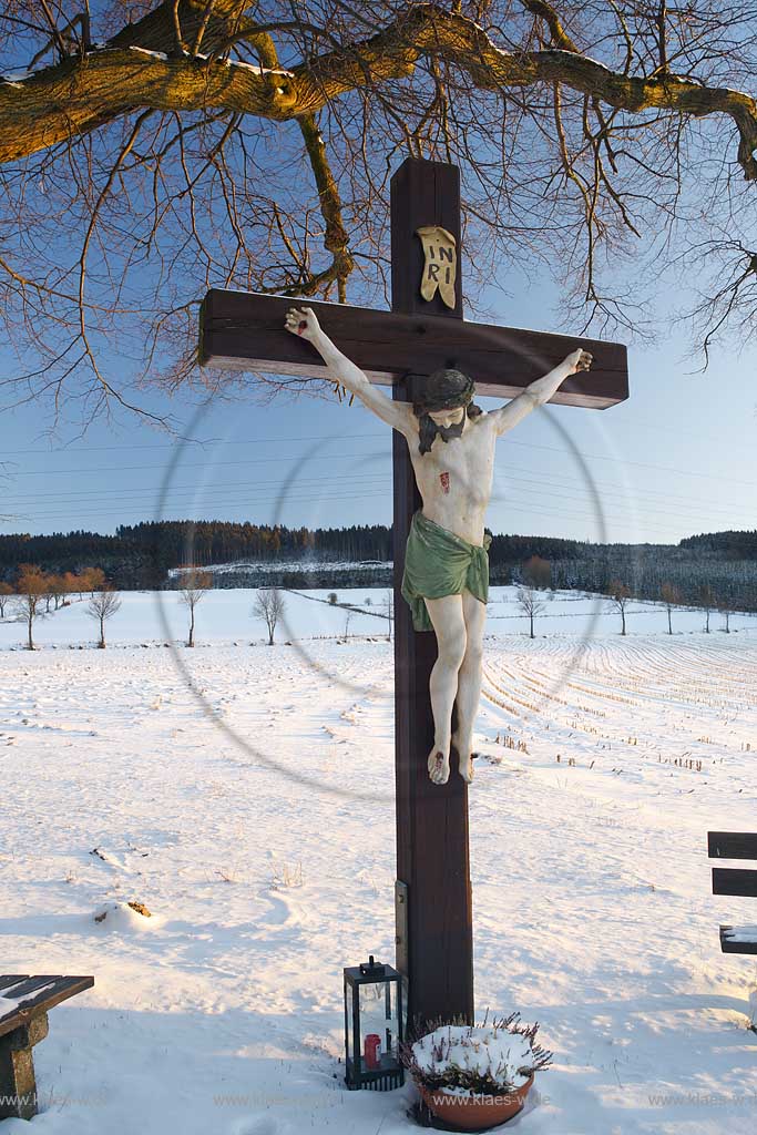 Schmallenberg Flurkreuz in verscheiter Winterlandschaft im warmen Licht der tief stehenden Abendsonne; Cruzifix in snow-covered winter landscape in warm light of evening sun.