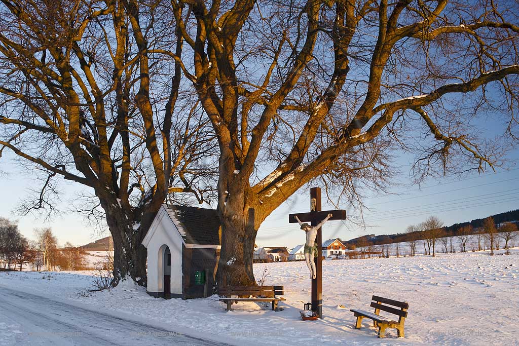 Schmallenberg Flurkreuz in verscheiter Winterlandschaft im warmen Licht der tief stehenden Abendsonne; Cruzifix in snow-covered winter landscape in warm light of evening sun.