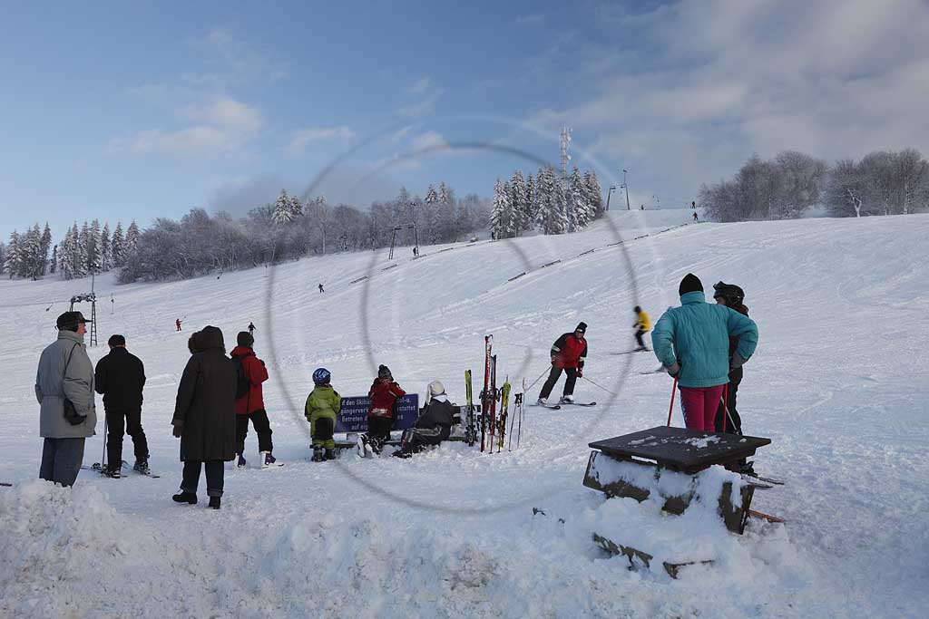 Sundern Wildewiese, Skigebiet mit Skipiste Lift und Skifahrern am verschneiten Hang des Schomberg mit Skilift und Mobilfunkmast, -turm im Winter; Skiing region Wildewiese with skier and ski tourists at the downhill of Schomberg with ski lift and mobilephone mast in Sundern-Wildewiese