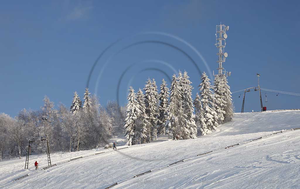 Sundern Wildewiese, Skigebiet mit Skipiste Lift und Skifahrern am verschneiten Hang des Schomberg mit Skilift und Mobilfunkmast, -turm im Winter; Skiing region Wildewiese with skier and ski tourists at the downhill of Schomberg with ski lift and mobilephone mast in Sundern-Wildewiese