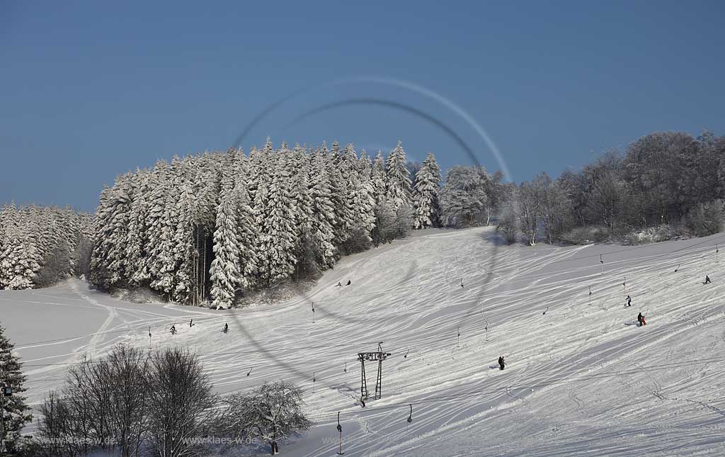 Sundern Wildewiese, Skigebiet mit Skipiste Lift und Skifahrern am verschneiten Hang des Schomberg mit Skilift und Mobilfunkmast, -turm im Winter; Skiing region Wildewiese with skier and ski tourists at the downhill of Schomberg with ski lift and mobilephone mast in Sundern-Wildewiese