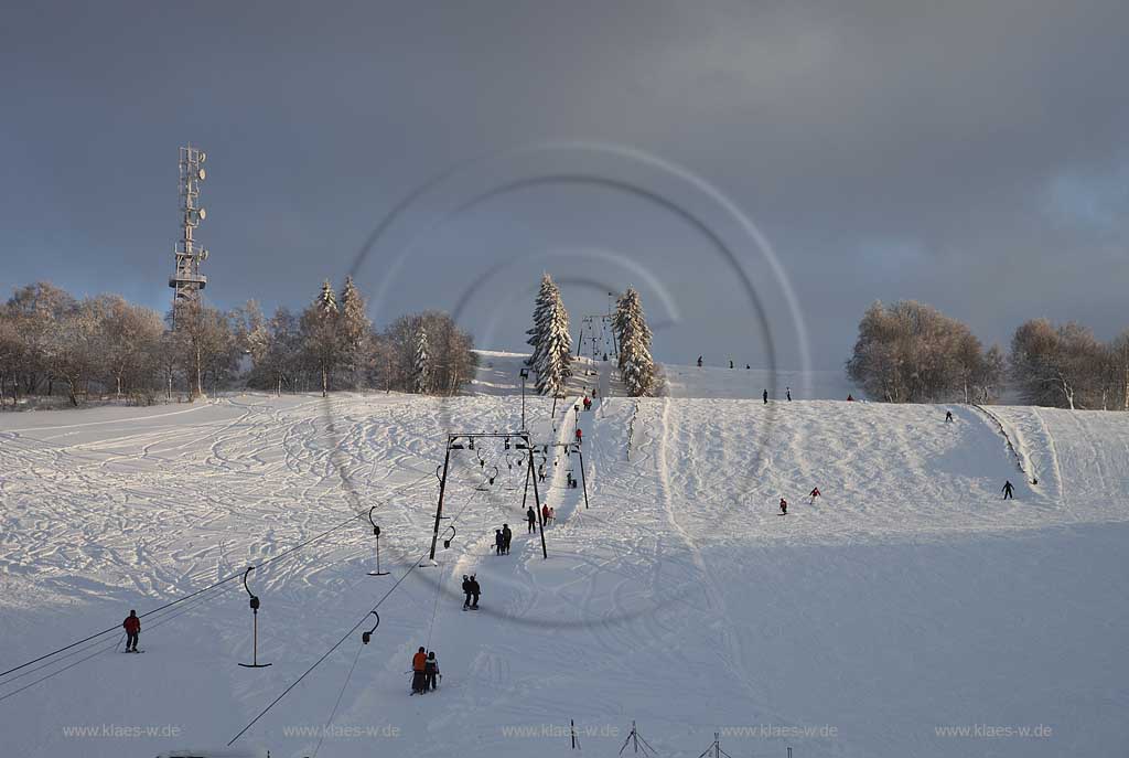 Sundern Wildewiese, Skigebiet mit Skipiste Lift und Skifahrern am verschneiten Hang des Schomberg mit Skilift und Mobilfunkmast, -turm im Winter; Skiing region Wildewiese with skier and ski tourists at the downhill of Schomberg with ski lift and mobilephone mast in Sundern-Wildewiese