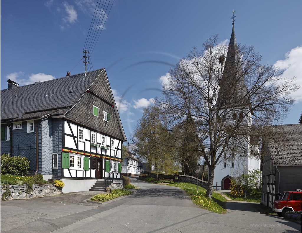 Freudenberg Oberhoklzklau, Pfarrhaus, das aelteste Fachwerkhaus des Siegerlandes, von 1608, rechts der Turm der evangelischen Pfarrkirche, einer suedwestfaelischen Hallenkirche im Fruehling; Freudenberg Oberholzklau, the oldes framework house in the Siegerland,  from 1608 and the tower of  parish church