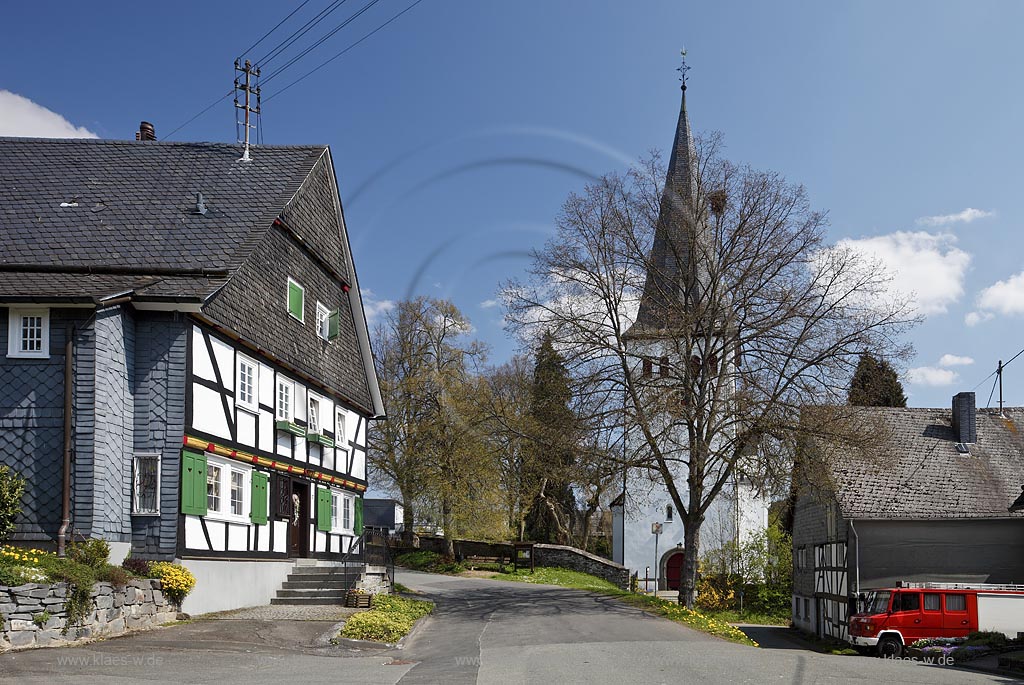 Freudenberg Oberhoklzklau, Pfarrhaus, das aelteste Fachwerkhaus des Siegerlandes, von 1608, rechts der Turm der evangelischen Pfarrkirche, einer suedwestfaelischen Hallenkirche im Fruehling; Freudenberg Oberholzklau, the oldes framework house in the Siegerland,  from 1608 and the tower of  parish church