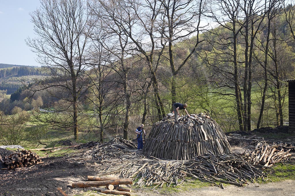 Netphen Walpersdorf, Kohlenmeiler Walpersdorf, einziger noch betriebener Kohlenmeiler im Siegerland. Die Koehlerei zur Herstellung von Holzkohle hat im Siegerland auf Grund der Eisenverhuettung eine lange Tradition; Netphan Walpersdorf traditional charcoal kiln in springtime landscape